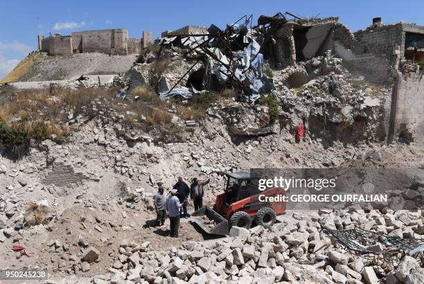 General view shows bulldozers shifting rubble as Syrians restore the al-Saffahiyah area in the old city of Aleppo on April 22, 2018. - Following a...