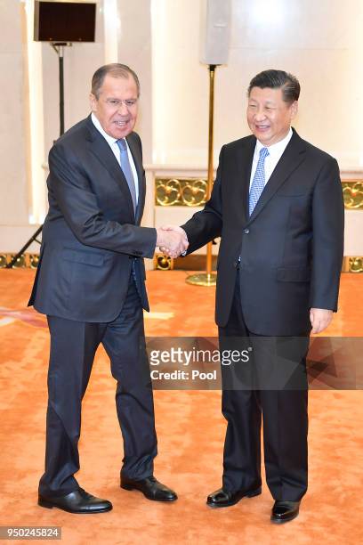 Russian Foreign Minister Sergei Lavrov shakes hands with Chinese President Chinese President Xi Jinping before a meeting at the Great Hall of the...