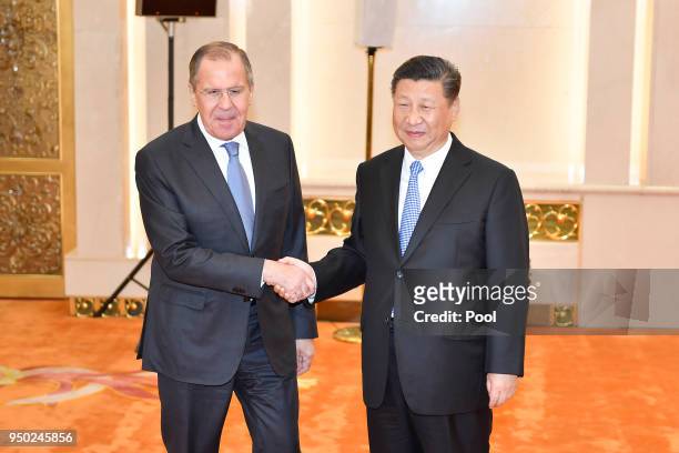 Russian Foreign Minister Sergei Lavrov shakes hands with Chinese President Chinese President Xi Jinping before a meeting at the Great Hall of the...