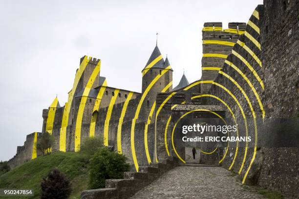 Tourists visit the medieval city of Carcassonne on April 23 whose walls are partly covered with yellow concentric circles created by the Paris-based,...