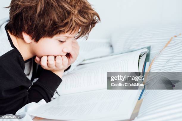 kid reading a book in bed - click&boo stock pictures, royalty-free photos & images