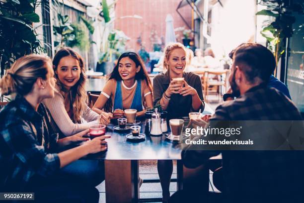 multi-ethnic group of hipster friends having fun at urban cafe - female with friend in coffee stock pictures, royalty-free photos & images