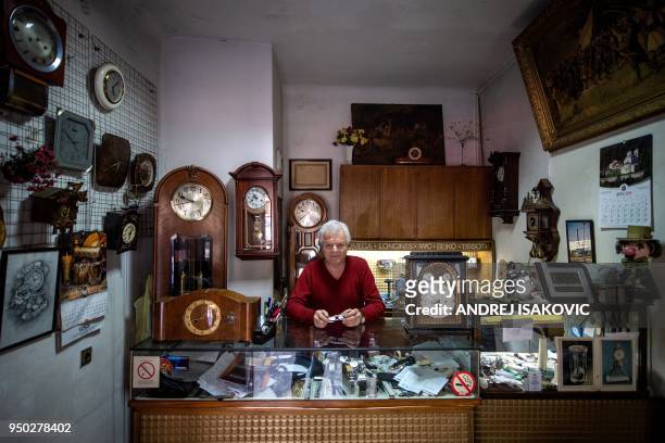 Dragan Dragas poses for a picture in his five decades old watchmaker repair shop in Belgrade on April 23, 2018. - Dragan has learned his watchmaking...