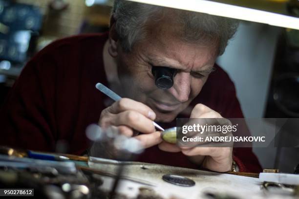 Dragan Dragas repairs a watch in his five decades old watchmaker repair shop in Belgrade on April 23, 2018. - Dragan has learned his watchmaking...