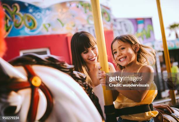 petite fille métisse, s’amuser avec la mère sur le tour de carrousel - fête foraine photos et images de collection