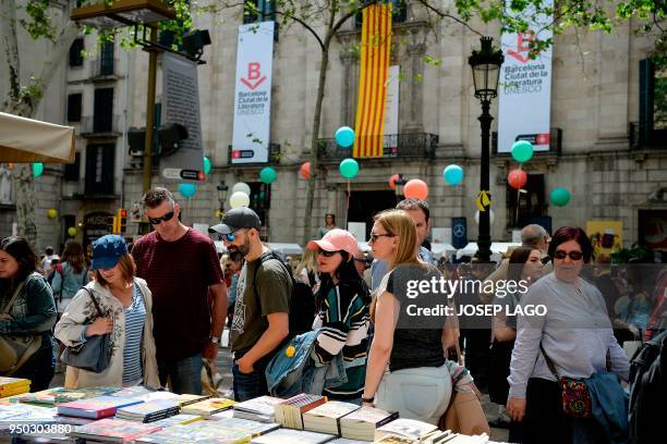 People look at books on the Ramblas boulevard during Sant Jordi festivities in Barcelona on April 23 on Saint George's day. - Traditionally men give...