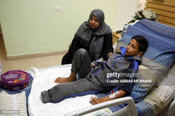 Abdel Rahman Nawfal sits next to his grandmother in a hospital in the West Bank city of Ramallah on April 23 after his leg was amputated following an...