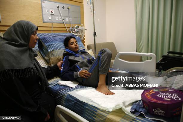 Abdel Rahman Nawfal sits next to his grandmother in a hospital in the West Bank city of Ramallah on April 23 after his leg was amputated following an...