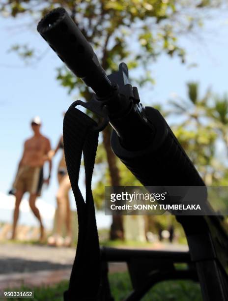 In this photograph taken on November 13, 2011 a tourist rides a bicycle where armed Indonesian marine policemen posted at the beach area in Nusa Dua...
