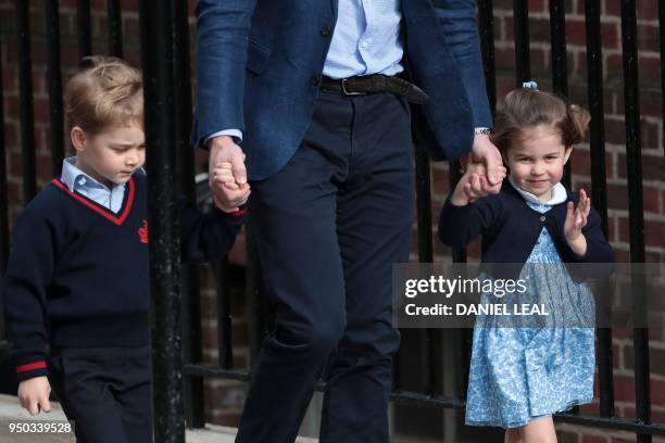 Princess Charlotte of Cambridge waves at the media as she is led in with her brother Prince George of Cambridge by their father Britain's Prince...