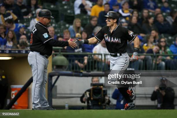 Derek Dietrich of the Miami Marlins and third base coach Fredi Gonzalez celebrate after Dietrich in the first inning against the Milwaukee Brewers at...