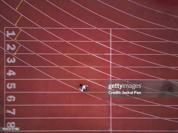 a man walking on an empty track and field stadium - estadio de atletismo fotografías e imágenes de stock