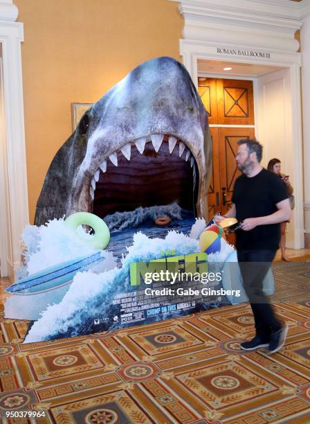 An attendee walks by an interactive advertisement for the upcoming "The Meg" movie at Caesars Palace during CinemaCon, the official convention of the...