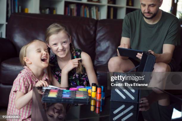 two laughing children plotting to put makeup on their oblivious father - oblivious stock pictures, royalty-free photos & images