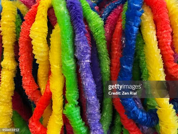 bunch of colorful paper lei or garland on display for retail sale - hawaiian lei stockfoto's en -beelden
