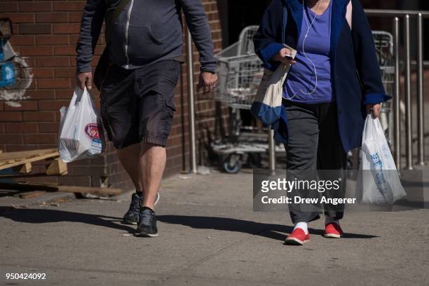 Shoppers carry plastic shopping bags as they leave a grocery store on Atlantic Avenue, April 23, 2018 in the Brooklyn borough of New York City. New...