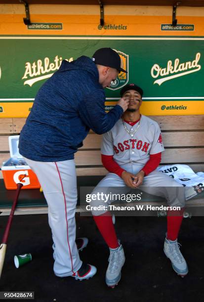 Mookie Betts of the Boston Red Sox has eye black put on by a teammate in the dugout prior to the start of his game against the Oakland Athletics at...