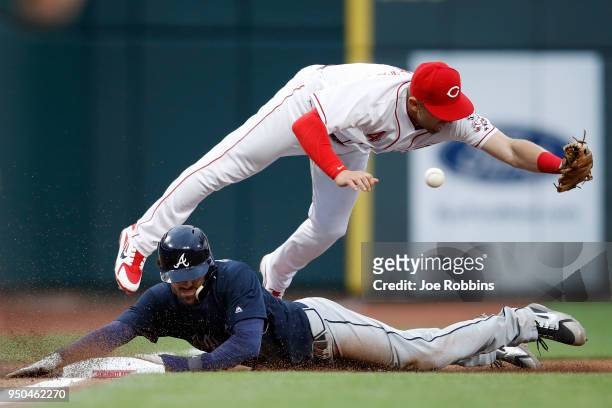 Dansby Swanson of the Atlanta Braves slides at third base ahead of the throw to Cliff Pennington of the Cincinnati Reds in the third inning of a game...