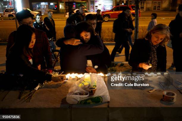 People embrace as they lay candles and leave messages at a memorial for victims of a crash on Yonge St. At Finch Ave., after a van plowed into...