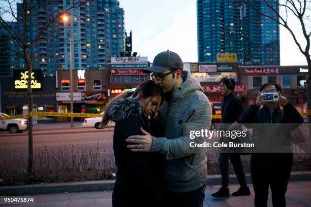 People embrace at the scene of a memorial for victims of a crash at Yonge St. At Finch Ave., after a van plowed into pedestrians on April 23, 2018 in...