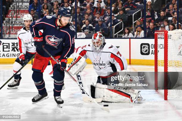 Alexander Wennberg of the Columbus Blue Jackets attempts to gain possession of the puck as goaltender Braden Holtby of the Washington Capitals...