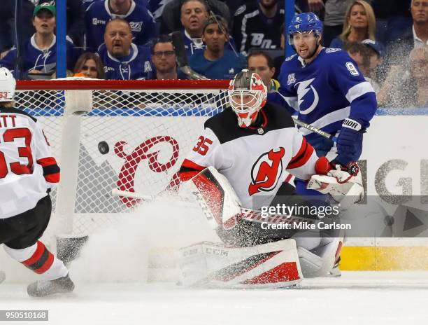 Cory Schneider of the New Jersey Devils makes a save as Tyler Johnson of the Tampa Bay Lightning looks on in the third period of Game Five of the...