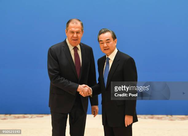 Russian Foreign Minister Sergei Lavrov shakes hands with Chinese State Councilor and Foreign Minister Wang Yi before a meeting of foreign ministers...
