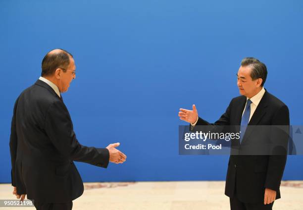 Russian Foreign Minister Sergei Lavrov moves to shake hands with Chinese State Councilor and Foreign Minister Wang Yi before a meeting of foreign...
