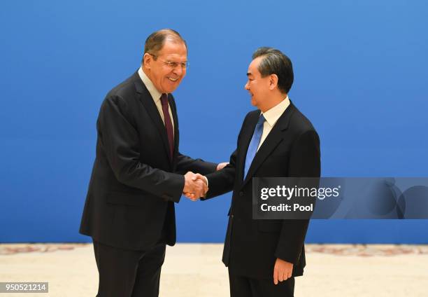 Russian Foreign Minister Sergei Lavrov shakes hands with Chinese State Councilor and Foreign Minister Wang Yi before a meeting of foreign ministers...