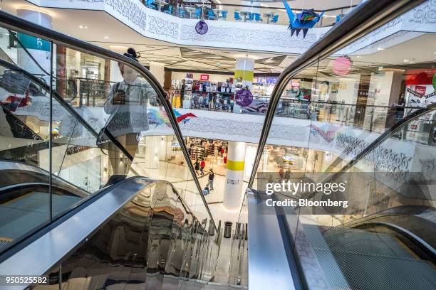 Woman looks at her cell phone while riding an escalator inside the Asia Mall shopping and entertainment center in Bishkek, Kyrgyzstan, on Friday,...