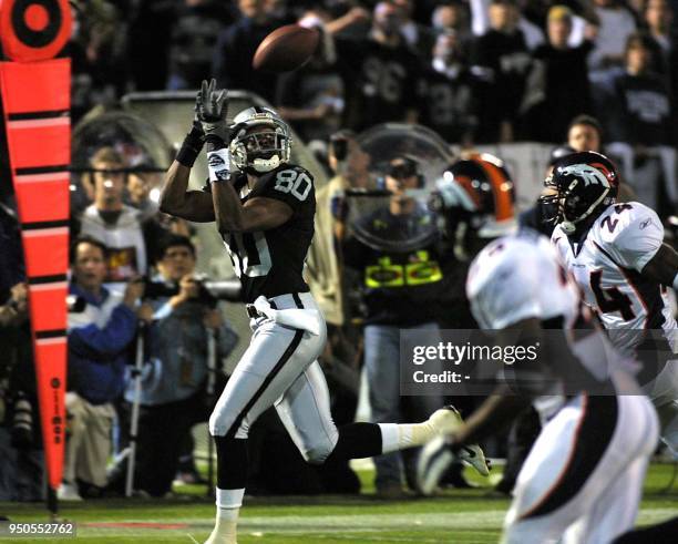 Oakland Raiders wide-receiver Jerry Rice hauls in a catch from Raiders quarterback Rich Gannon as Denver Broncos cornerback Deltha O'Neal and Broncos...