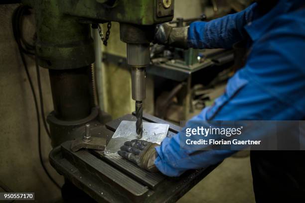 Worker drills a metal plate in a blacksmith shop on April 03, 2018 in Klitten, Germany.