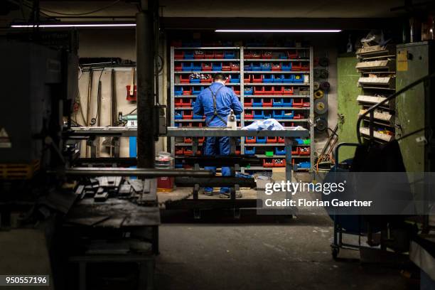 Worker stands in front of a shelf with screws in the workshop of a blacksmith on April 03, 2018 in Klitten, Germany.