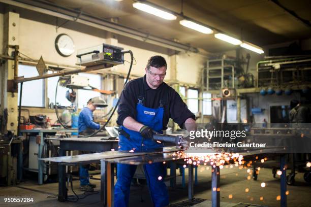 Worker grinds metal in the workshop of a blacksmith on April 03, 2018 in Klitten, Germany.