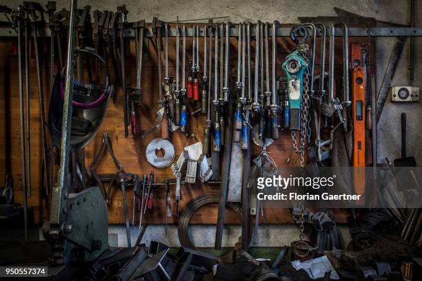 Above a workbench, various tools hang on the wall. Photo taken in the workshop of a blacksmith on April 03, 2018 in Klitten, Germany.
