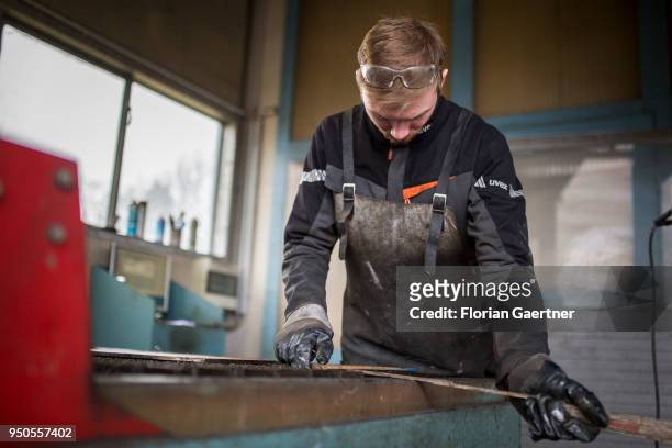 Young worker uses a folding rule to measure a metal plate in the workshop of a blacksmith on April 03, 2018 in Klitten, Germany.