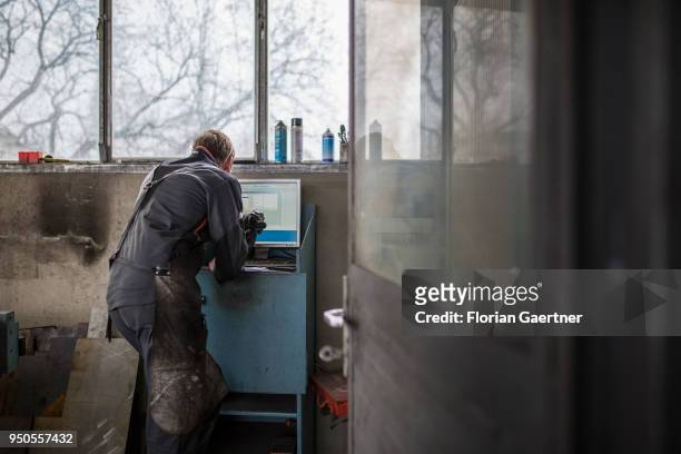 Young craftsman is working on a computer in the workshop of a blacksmith on April 03, 2018 in Klitten, Germany.