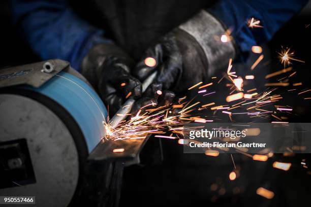 Worker grinds a metal bar in the workshop of a blacksmith on April 03, 2018 in Klitten, Germany.
