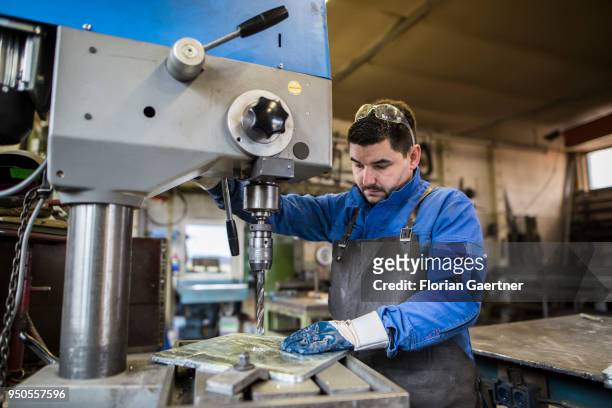 Worker drills a metal plate in the workshop of a blacksmith on April 03, 2018 in Klitten, Germany.