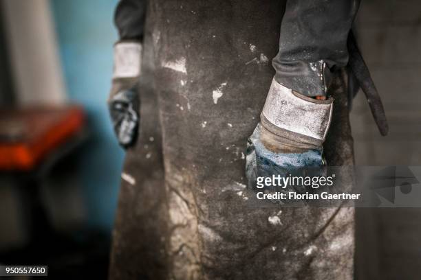 Closeup of a worker wearing work gloves and apron taken in a blacksmith shop on April 03, 2018 in Klitten, Germany.