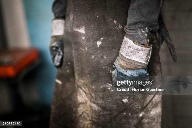 Closeup of a worker wearing work gloves and apron taken in a blacksmith shop on April 03, 2018 in Klitten, Germany.