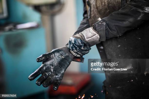 Worker puts on his protective gloves in a blacksmith shop on April 03, 2018 in Klitten, Germany.