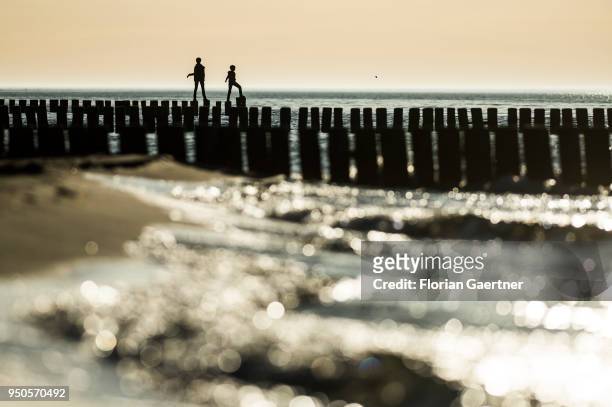 Two people balance on groynes at the Baltic Sea on April 21, 2018 in Warnemuende, Germany.