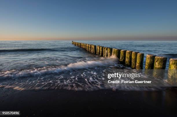 Groynes are pictured during sunset on April 21, 2018 in Warnemuende, Germany.