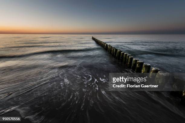 Groynes are pictured after sunset on April 21, 2018 in Warnemuende, Germany.