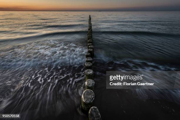 Groynes are pictured after sunset on April 21, 2018 in Warnemuende, Germany.