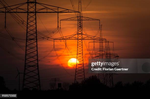 Electricity pylons are pictured in front of the setting sun on April 22, 2018 in Nauen, Germany.