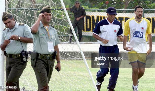 Defense player of the Colombian soccer team, Mario Yepes , jogs with assistent coach Alexis Garcia, while guarded by Colombian National Police...