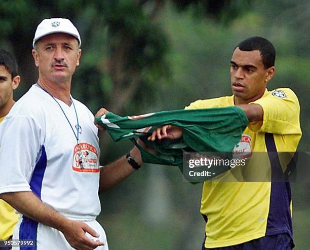 Head coach of the Brazilian soccer team, Luiz Felipe Scolari , hands a jersey over to starting player Denilson, 13 July 2001, during a practice in...