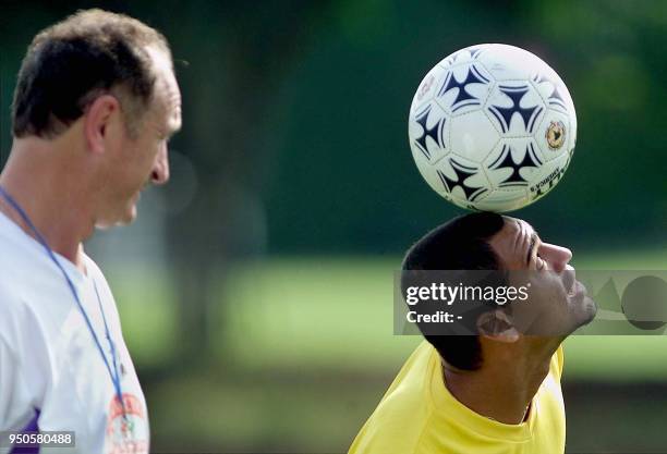 Denilson , striker of the Brazilian soccer team, controls the ball, while his coach, Luiz Felipe Scolari, watches, 10 July 2001, during their first...